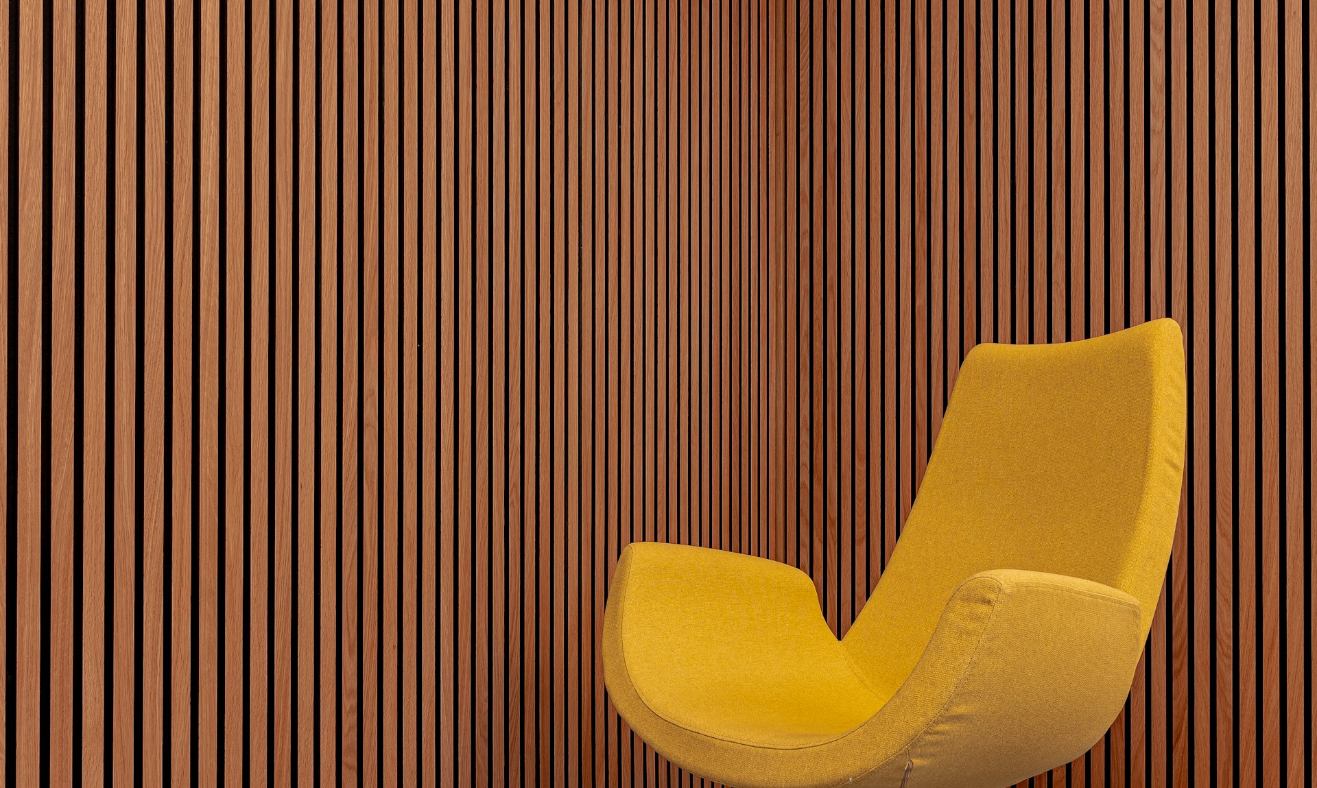 a yellow chair sitting in front of a wooden wall